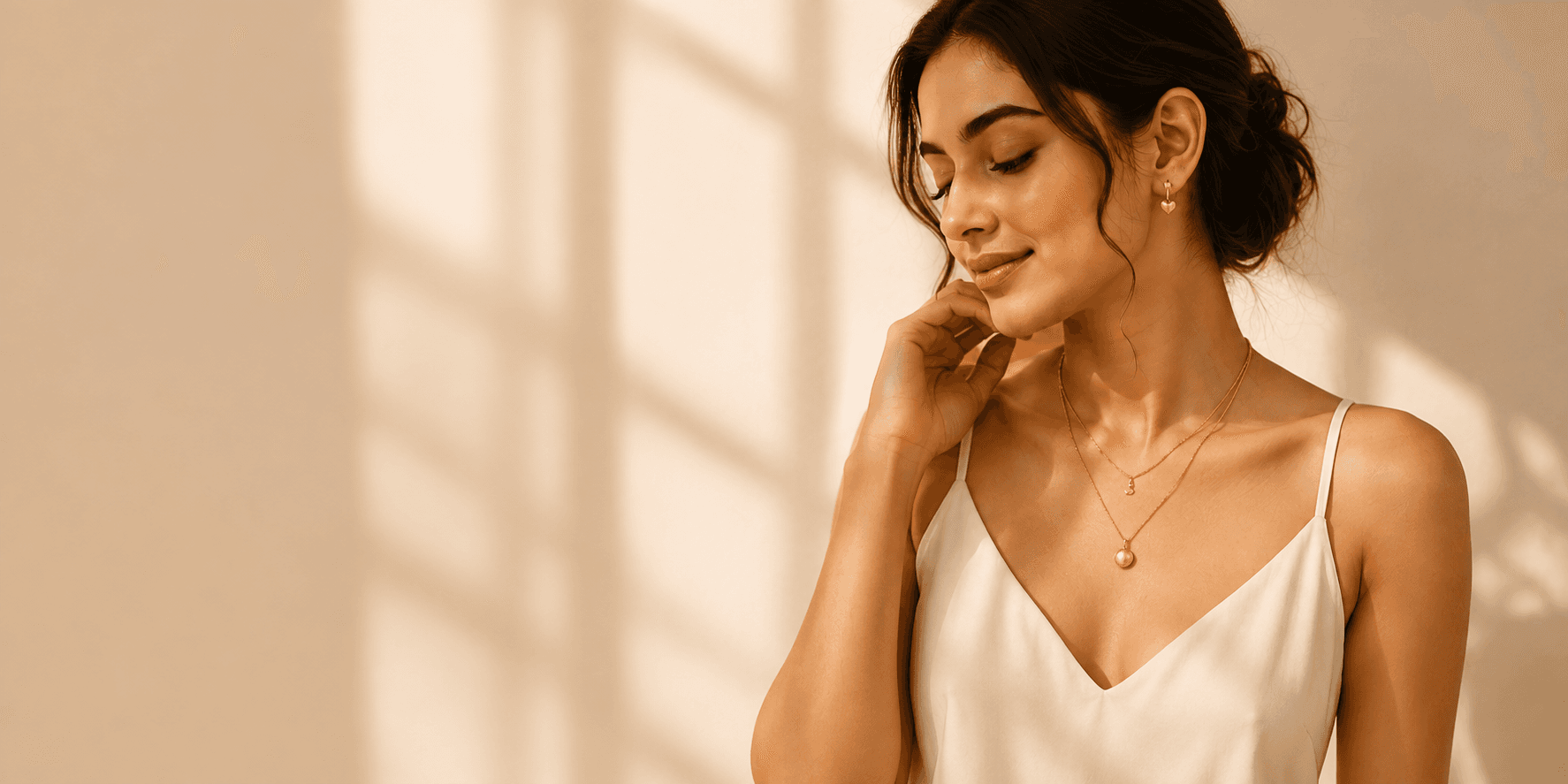 Woman wearing layered gold anti-tarnish necklaces and stud earrings in warm, golden-hour light